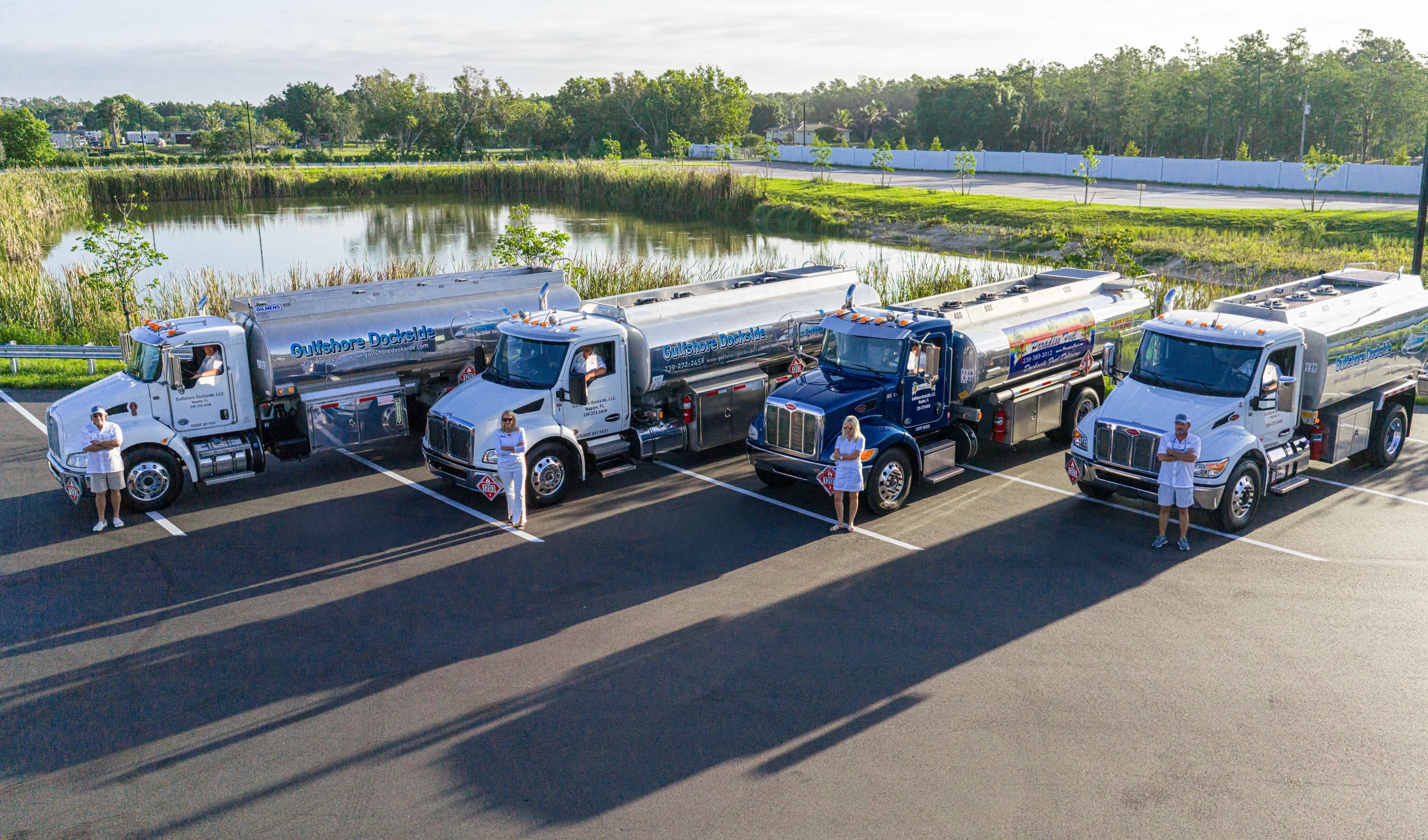 The four Gulfshore Dockside drivers standing at their polished tankers in the Naples yard at golden hour